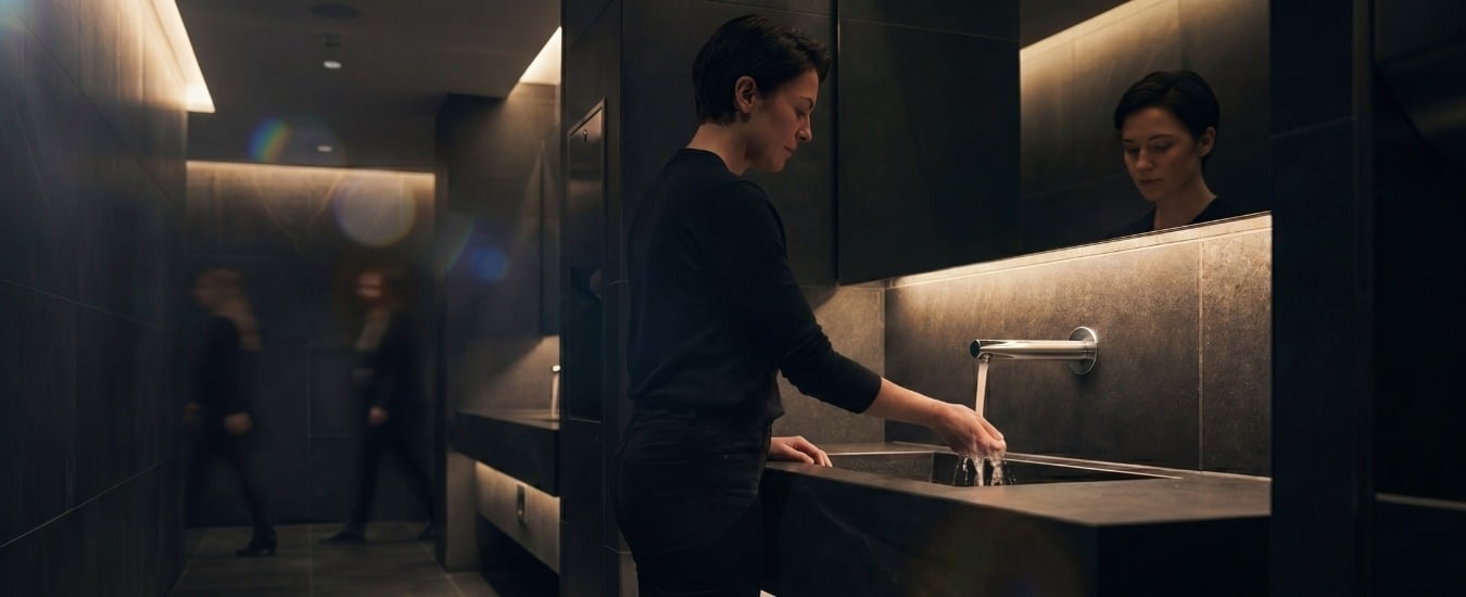 Image of Woman washing hands at modern washroom sink with sleek faucet and ambient lighting