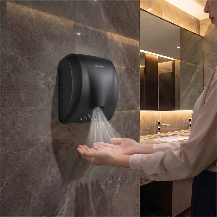 Image of A person using a Euronics Industries EH210N wall-mounted hand dryer in a modern restroom.